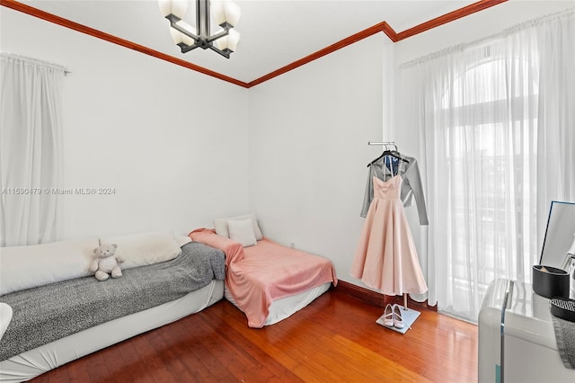 bedroom featuring crown molding, hardwood / wood-style flooring, and an inviting chandelier