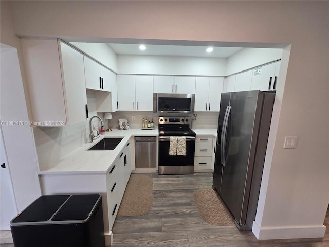 kitchen with appliances with stainless steel finishes, backsplash, dark wood-type flooring, sink, and white cabinetry