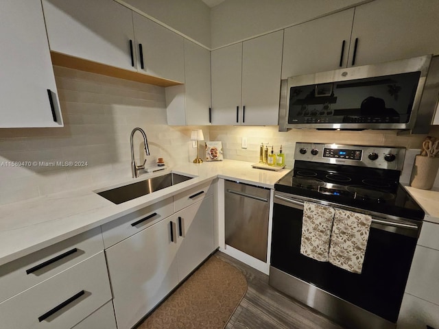 kitchen featuring light stone countertops, sink, stainless steel appliances, dark hardwood / wood-style flooring, and decorative backsplash