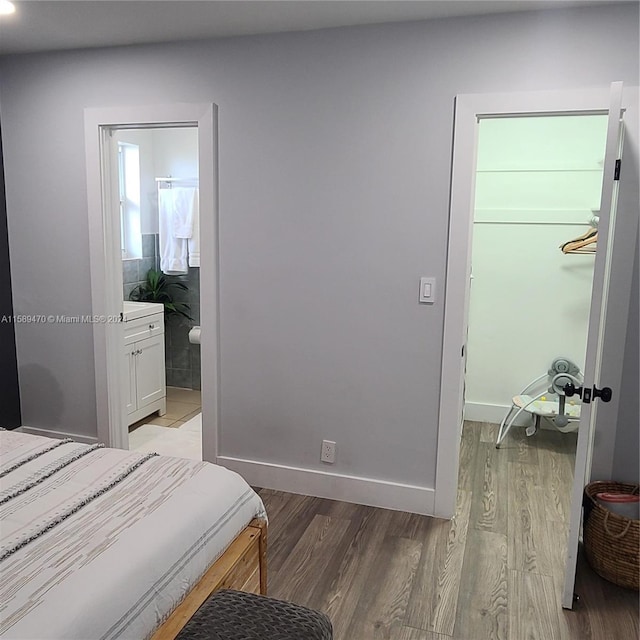 bedroom featuring a closet, light hardwood / wood-style flooring, ensuite bath, and a spacious closet