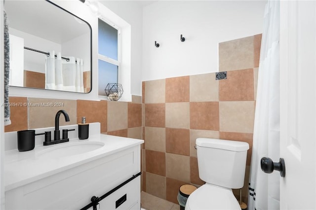 bathroom featuring vanity, toilet, and tile walls