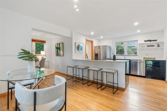 kitchen featuring stainless steel appliances, light hardwood / wood-style floors, plenty of natural light, and kitchen peninsula