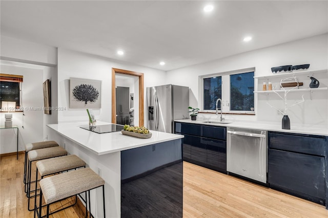 kitchen featuring a breakfast bar, a center island, sink, light hardwood / wood-style flooring, and appliances with stainless steel finishes