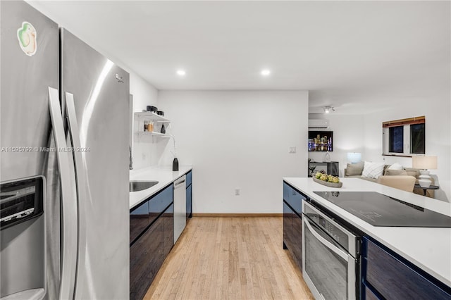 kitchen featuring blue cabinetry, appliances with stainless steel finishes, and light hardwood / wood-style flooring