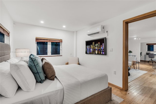 bedroom with light wood-type flooring and a wall mounted AC