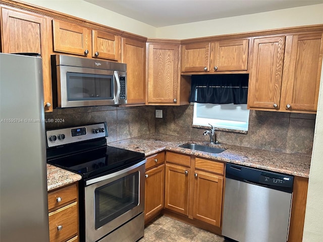 kitchen with decorative backsplash, light stone counters, sink, and stainless steel appliances