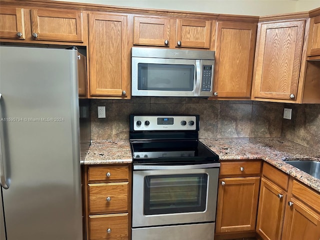 kitchen with light stone countertops, stainless steel appliances, and tasteful backsplash