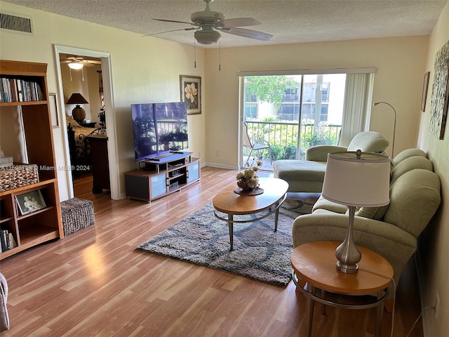 living room featuring hardwood / wood-style floors, a textured ceiling, and ceiling fan