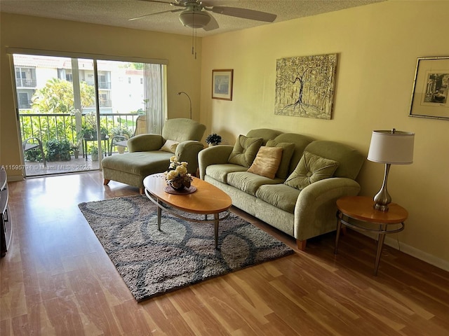 living room featuring wood-type flooring, a textured ceiling, and ceiling fan