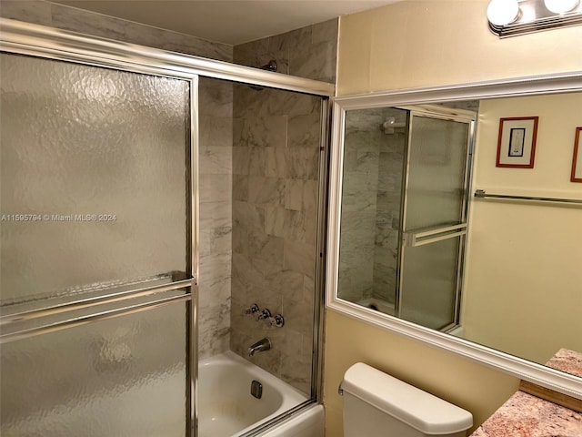 bathroom with toilet and bath / shower combo with glass door