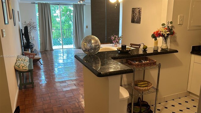 kitchen with dark stone countertops, kitchen peninsula, and parquet flooring