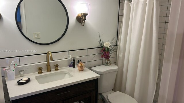 bathroom with tasteful backsplash, large vanity, and toilet