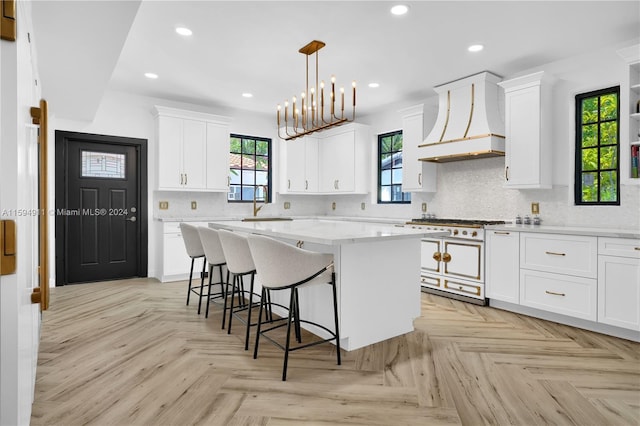 kitchen featuring high end range, white cabinetry, a kitchen island, and custom exhaust hood