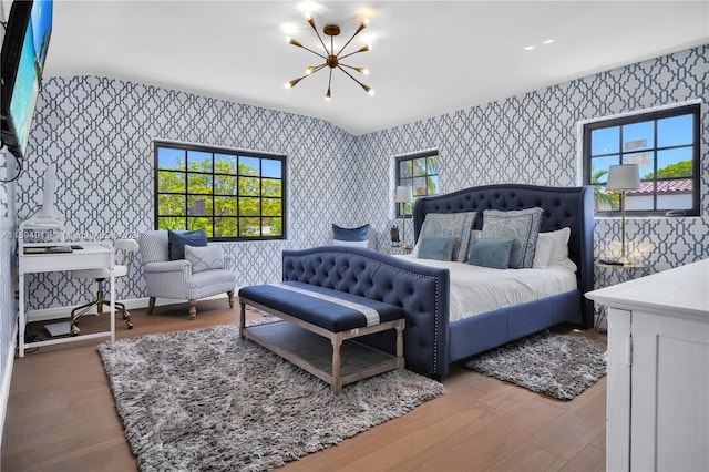 bedroom with an inviting chandelier, lofted ceiling, and hardwood / wood-style flooring