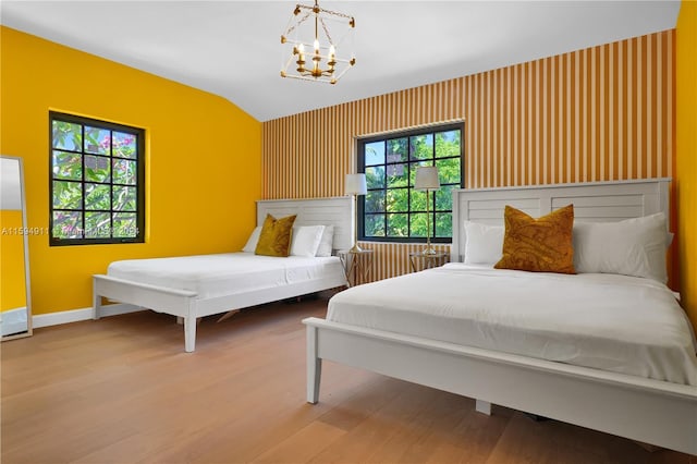 bedroom featuring an inviting chandelier, lofted ceiling, and hardwood / wood-style flooring