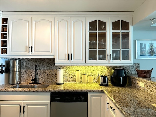 kitchen with white cabinets, backsplash, stainless steel dishwasher, and a sink