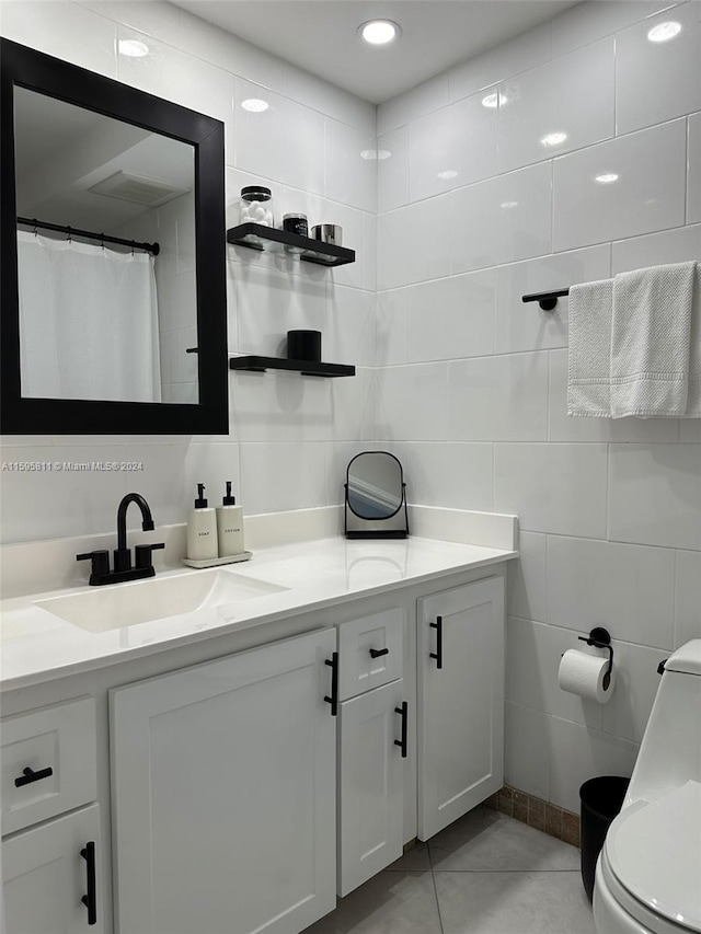 bathroom featuring tile flooring, vanity, toilet, and tile walls