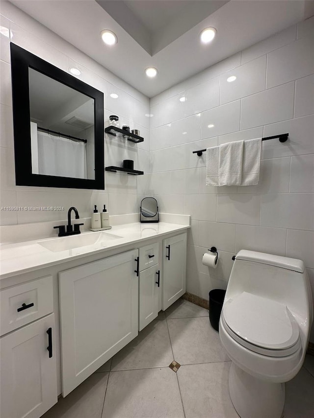 bathroom featuring tile flooring, vanity, toilet, and tile walls