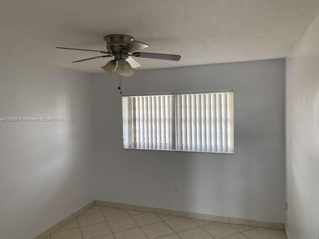 spare room with light tile patterned flooring, ceiling fan, and a textured ceiling