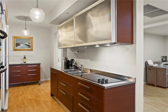 kitchen with pendant lighting, black electric stovetop, light wood-type flooring, and sink