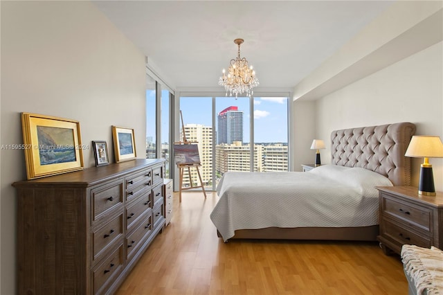 bedroom featuring expansive windows, light hardwood / wood-style floors, and a notable chandelier