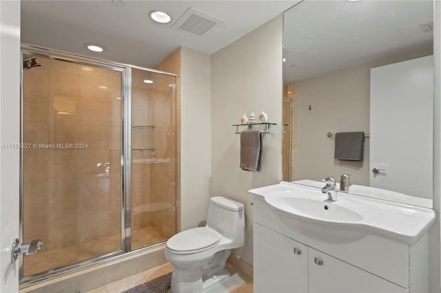 bathroom with tile patterned floors, vanity, a shower with shower door, and toilet