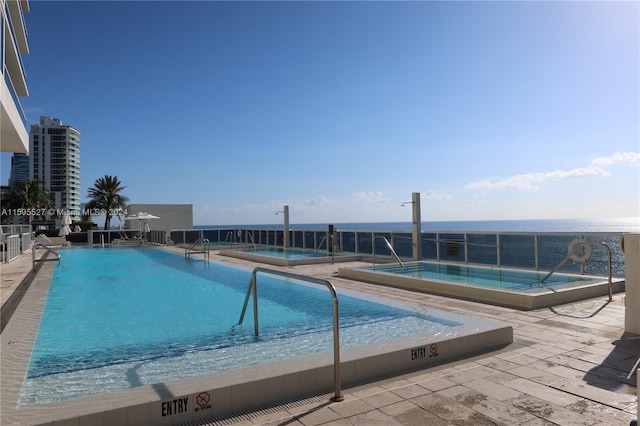 view of swimming pool featuring a patio and a water view