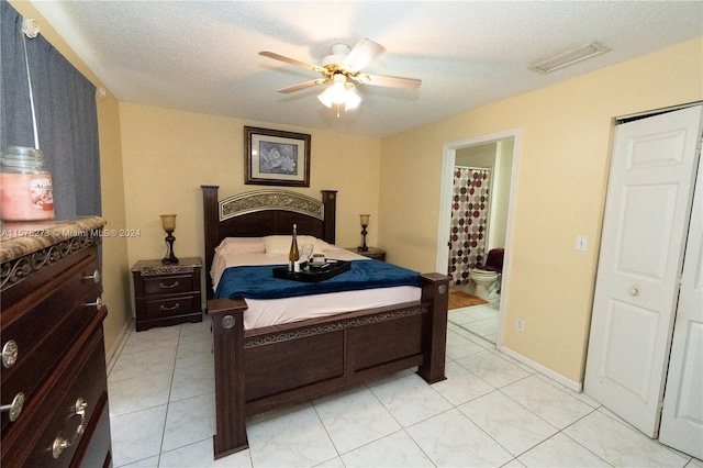 tiled bedroom with ceiling fan, ensuite bathroom, and a textured ceiling