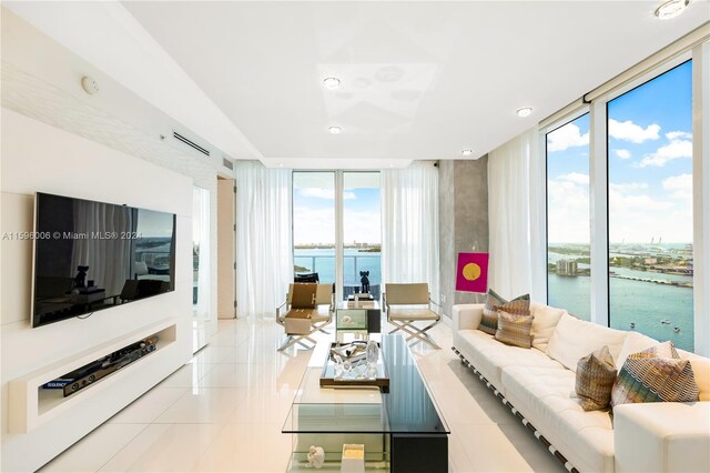 living room featuring floor to ceiling windows, a water view, plenty of natural light, and light tile floors