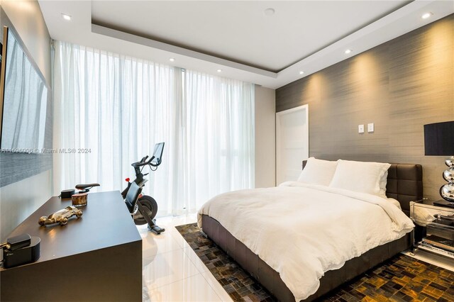 bedroom with dark tile flooring and a raised ceiling