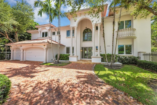 mediterranean / spanish-style home with stucco siding, decorative driveway, a garage, and fence