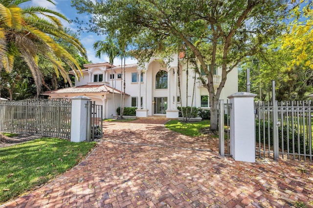 exterior space featuring a tile roof, a gate, a fenced front yard, and stucco siding