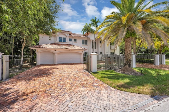 mediterranean / spanish house with stucco siding, decorative driveway, a fenced front yard, and a tiled roof