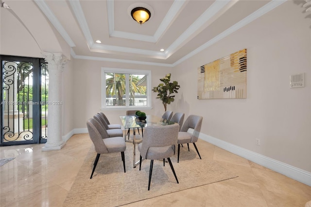 dining room with ornamental molding, a raised ceiling, and decorative columns