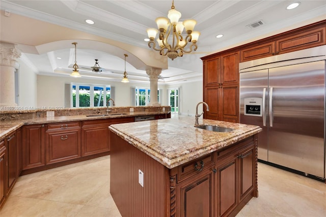 kitchen with built in refrigerator, a raised ceiling, a kitchen island with sink, and sink