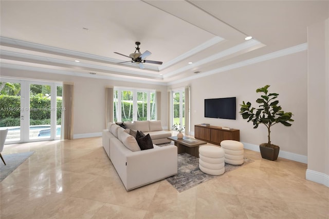 living room featuring a tray ceiling, ornamental molding, a wealth of natural light, and ceiling fan