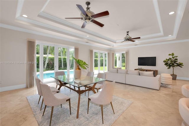 tiled dining room with ceiling fan, ornamental molding, and a tray ceiling