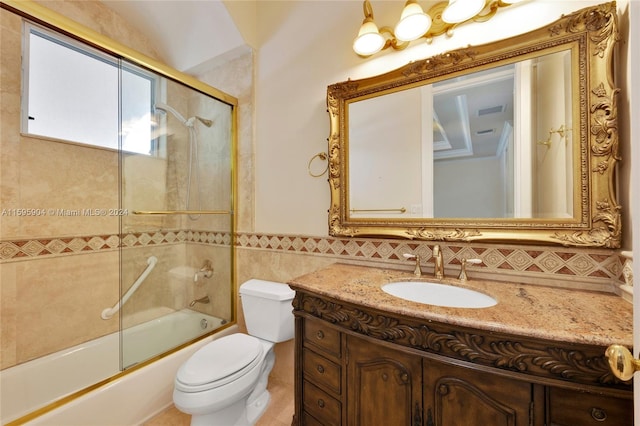 full bathroom featuring tile walls, toilet, bath / shower combo with glass door, and vanity