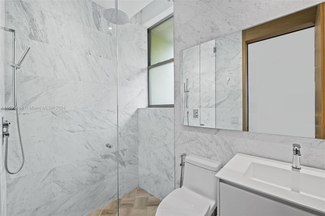 bathroom featuring vanity, toilet, tiled shower, and tile walls