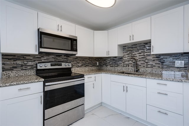 kitchen featuring stainless steel appliances, sink, white cabinetry, and backsplash