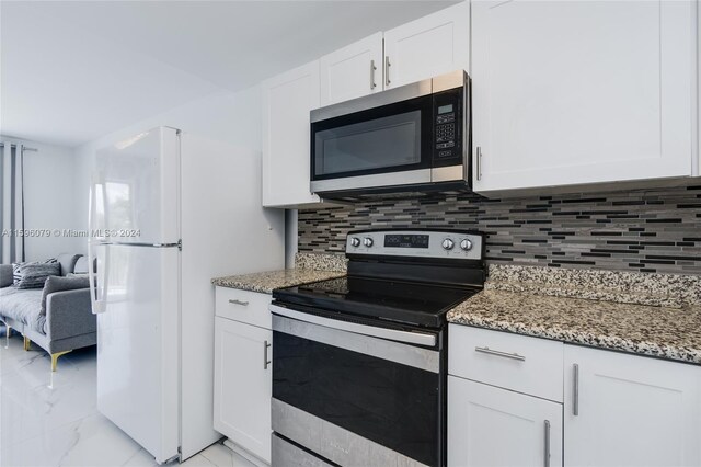 kitchen featuring light stone countertops, white cabinets, light tile floors, and stainless steel appliances