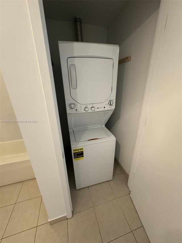 laundry room featuring stacked washing maching and dryer and light tile patterned floors