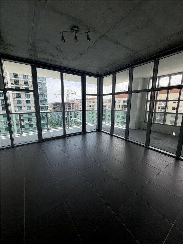 tiled empty room featuring floor to ceiling windows