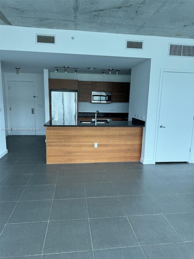 kitchen with sink, dark tile patterned flooring, and stainless steel appliances