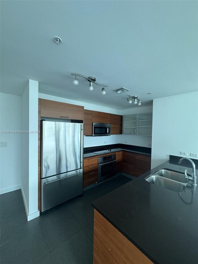 kitchen featuring sink, appliances with stainless steel finishes, rail lighting, and dark tile patterned floors