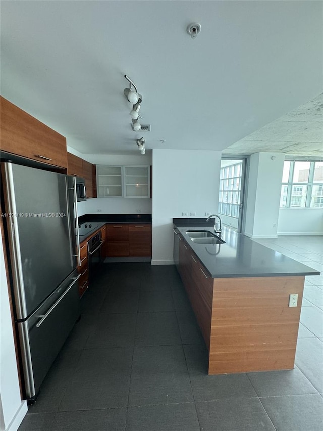 kitchen featuring appliances with stainless steel finishes, dark tile patterned floors, track lighting, sink, and kitchen peninsula