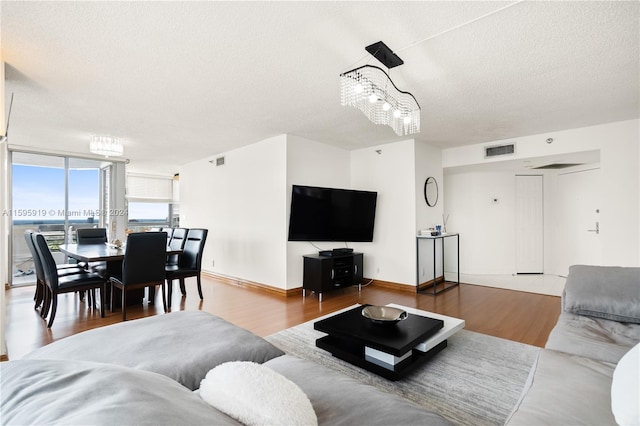 living room featuring an inviting chandelier, a textured ceiling, expansive windows, and wood-type flooring