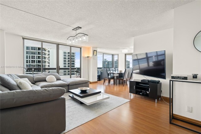 living room featuring a notable chandelier, a textured ceiling, wood-type flooring, and expansive windows