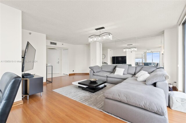 living room with a textured ceiling, hardwood / wood-style floors, and a chandelier