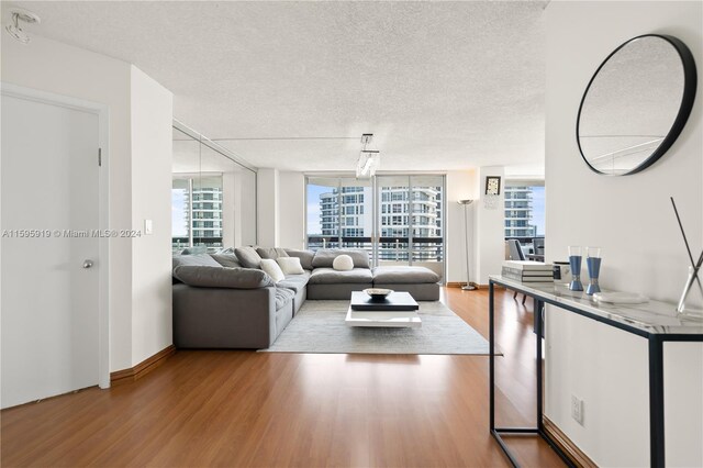 living room featuring a textured ceiling, wood-type flooring, and a wall of windows